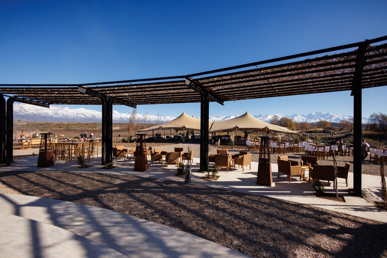 Cocktail area under a pergola with bedouin tents and high tables, the mountains rising behind the vineyard