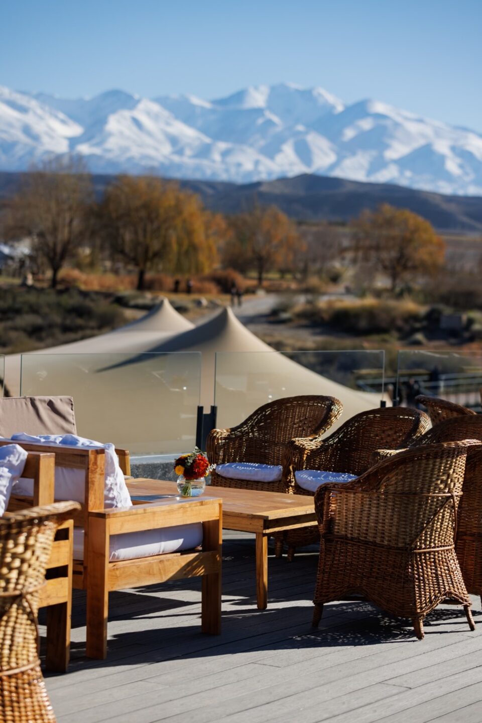 Wicker armchairs and a wooden table on a terrace beside a bedouin tent, with the snow-capped Andes in the distance